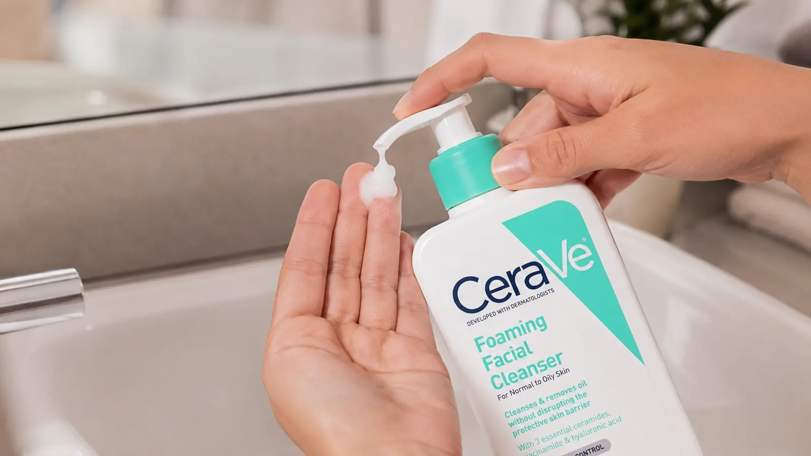 Hand pumping CeraVe Foaming Facial Cleanser onto fingertips at a bathroom sink