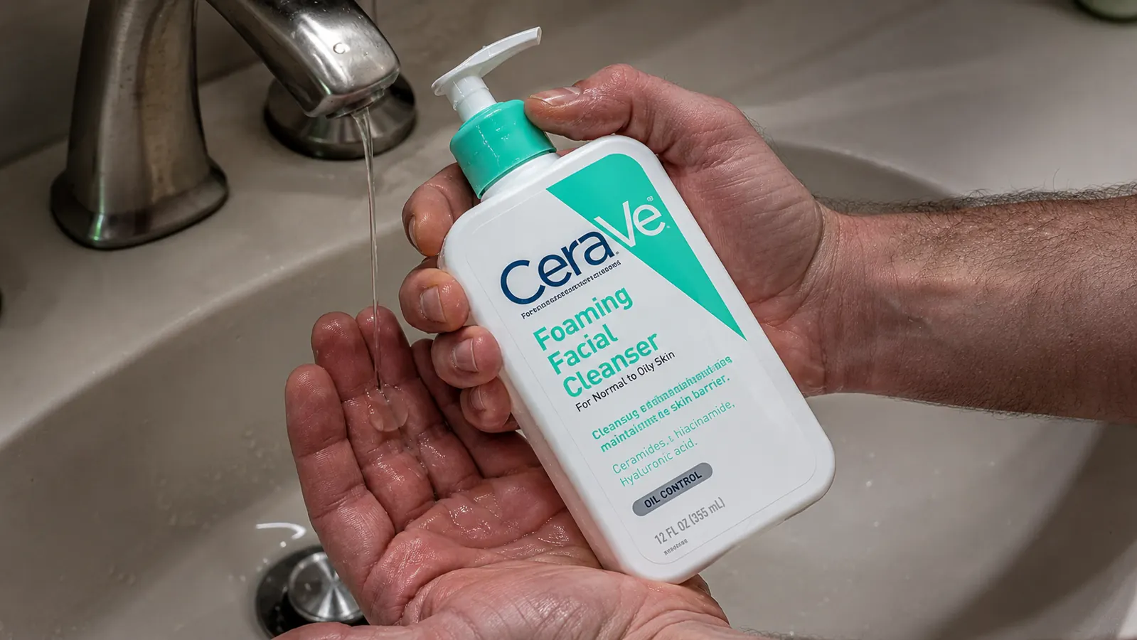 Hand holding the CeraVe Foaming Facial Cleanser bottle next to a sun-worn, calloused hand under harsh bathroom light