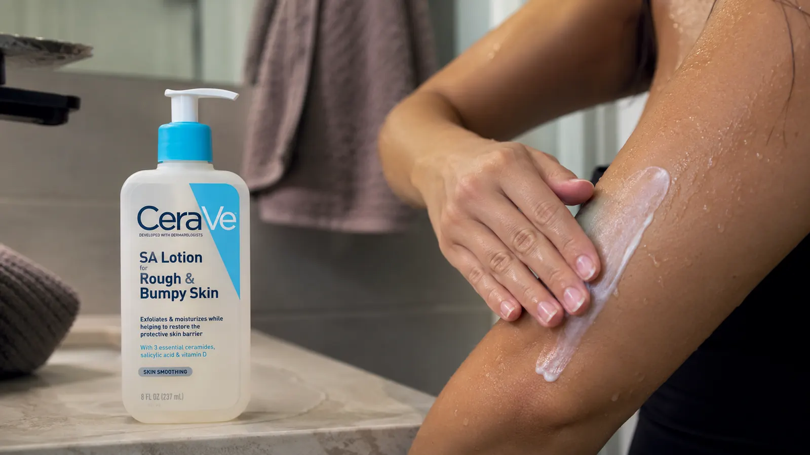 Hand smoothing CeraVe SA Lotion onto the back of an upper arm after a shower
