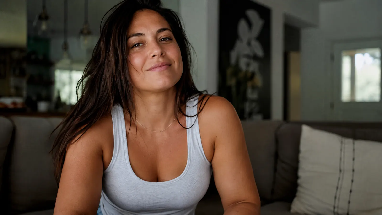 Woman in a tank top standing in soft morning light, arms relaxed at her sides