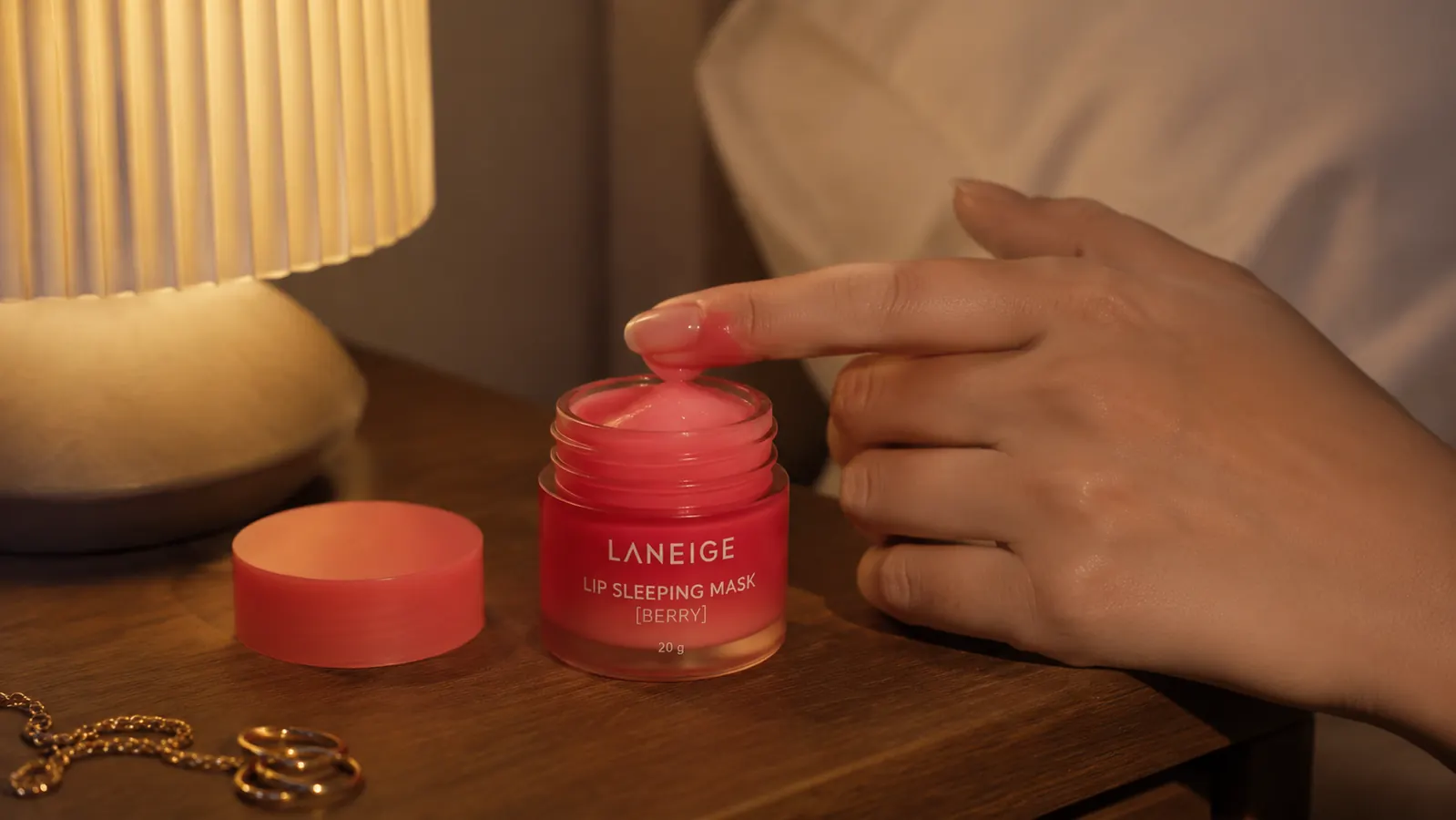 LANEIGE Lip Sleeping Mask jar open on a nightstand next to a lamp and a glass of water