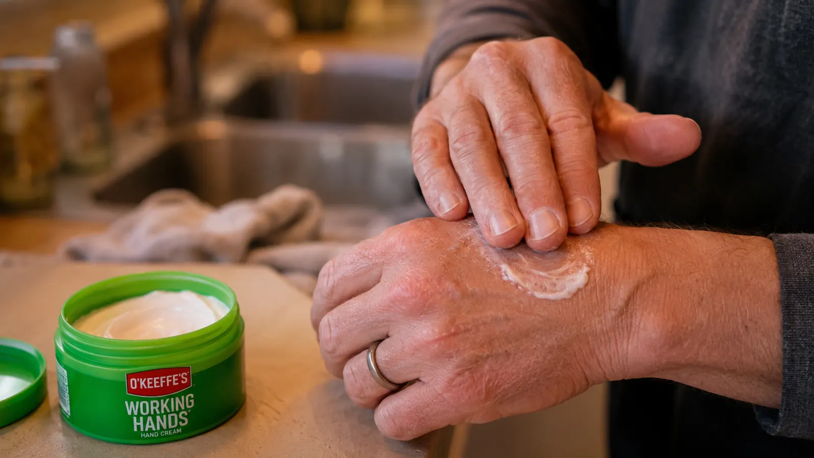 Close-up of hands rubbing cream into knuckles and cuticles after washing dishes